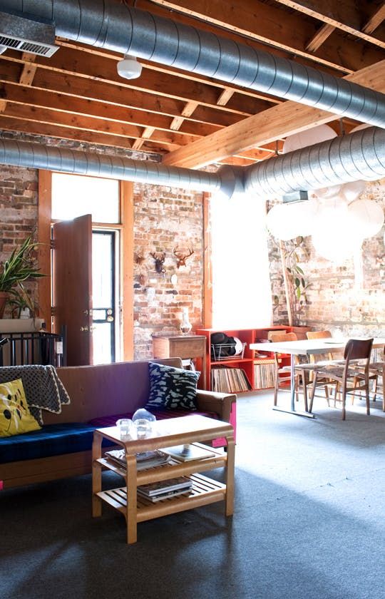 a living room filled with lots of furniture and exposed pipes on the ceiling above it