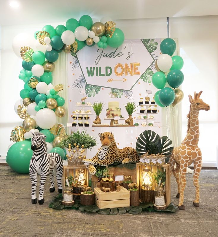 an animal themed birthday party with balloons and decorations on the wall, including giraffes