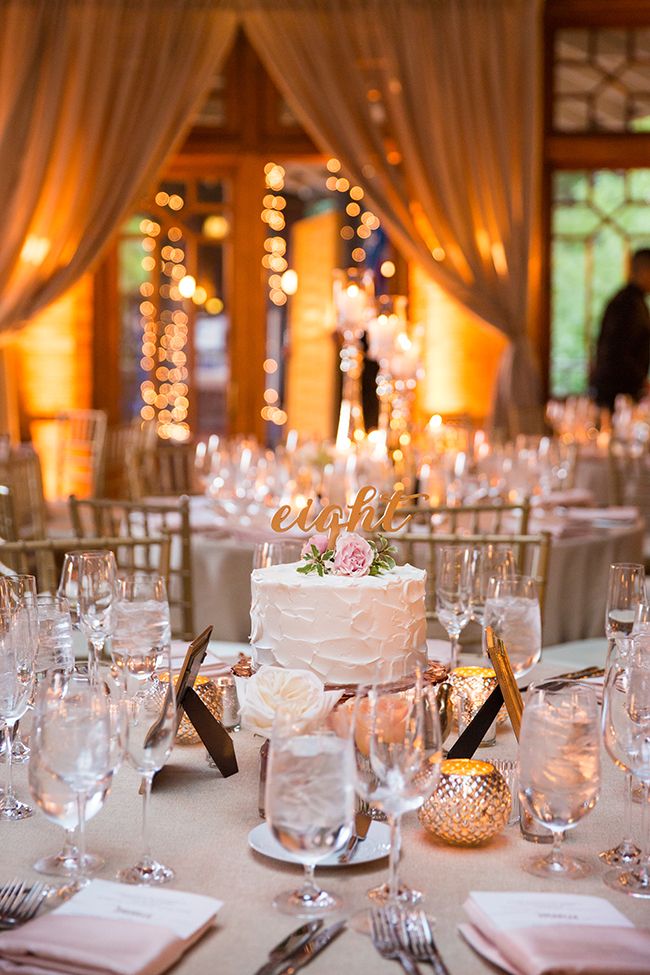 a wedding cake sitting on top of a table covered in white cloths and silverware