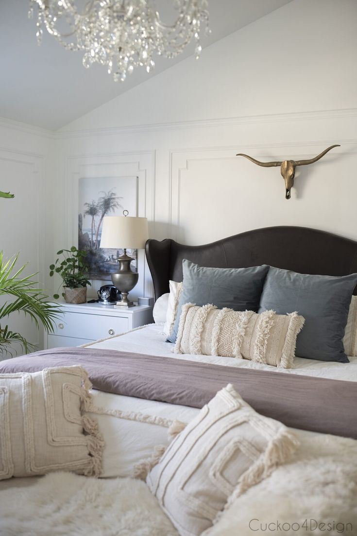 a bedroom with a bed, chandelier and pillows