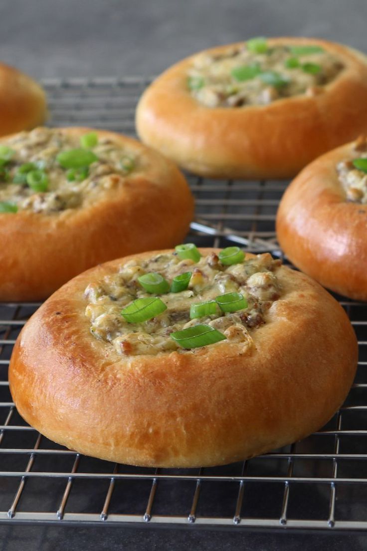 several breads with green onions and cheese on a cooling rack in front of them