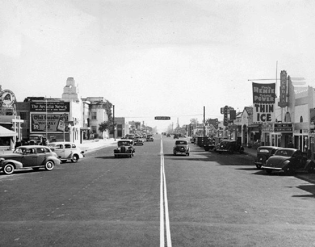 an old black and white photo of cars driving down the street