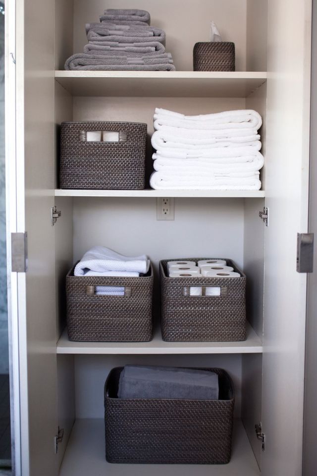 an organized closet with folded towels and baskets