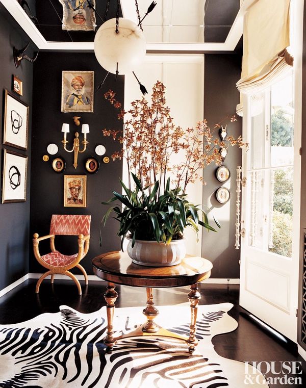 a living room with zebra print rug and pictures on the wall, chairs and table