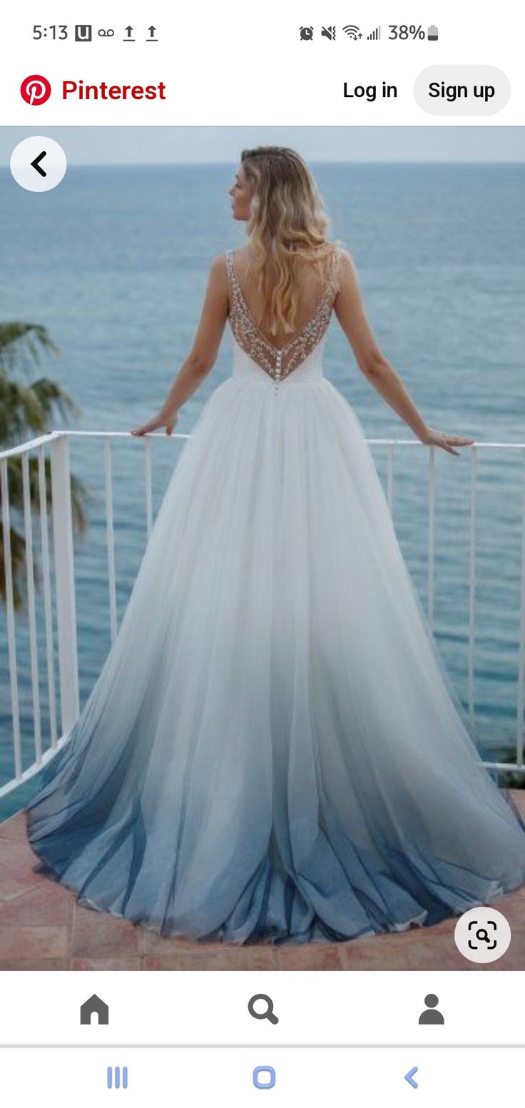 a woman in a wedding dress looking out over the ocean from a balcony overlooking palm trees