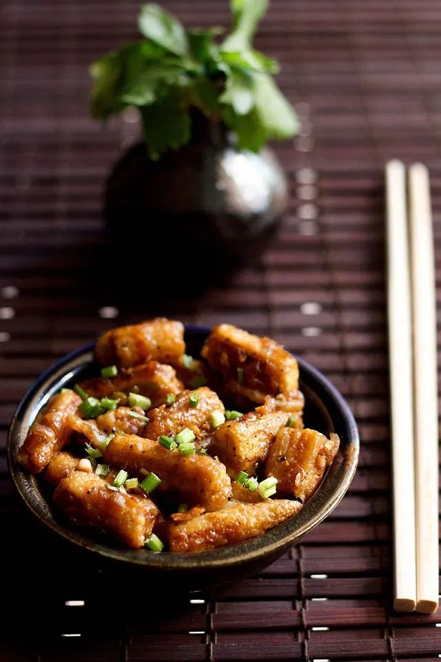 a bowl filled with fried food next to chopsticks