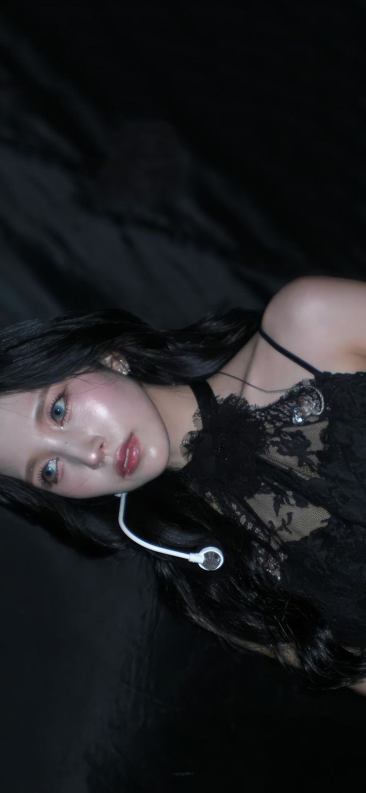 a woman with long black hair is wearing headphones and posing in front of a dark background