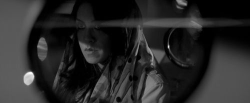 a woman looking through a magnifying glass with her face close to the camera