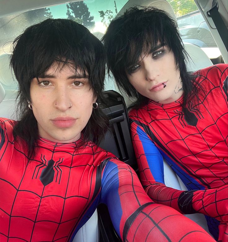 two people in spider man costumes sitting in the back seat of a car with their hands on their hips