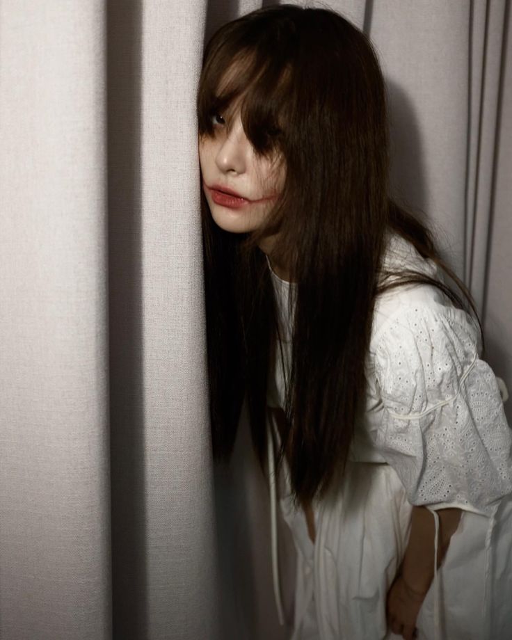 a woman with long hair standing behind a curtain