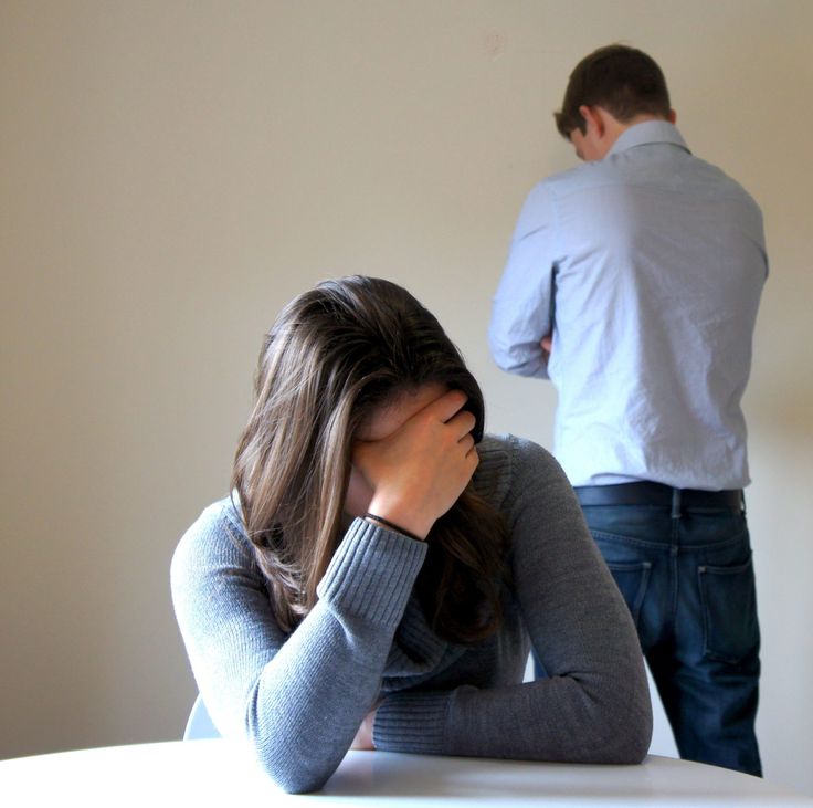 a man standing behind a woman sitting at a table