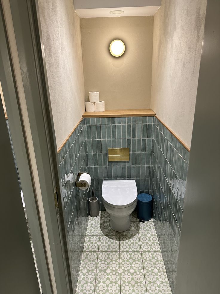 a small bathroom with a toilet in the corner and blue tiles on the walls,