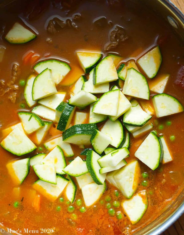 a pot filled with soup and sliced cucumbers on top of the stovetop