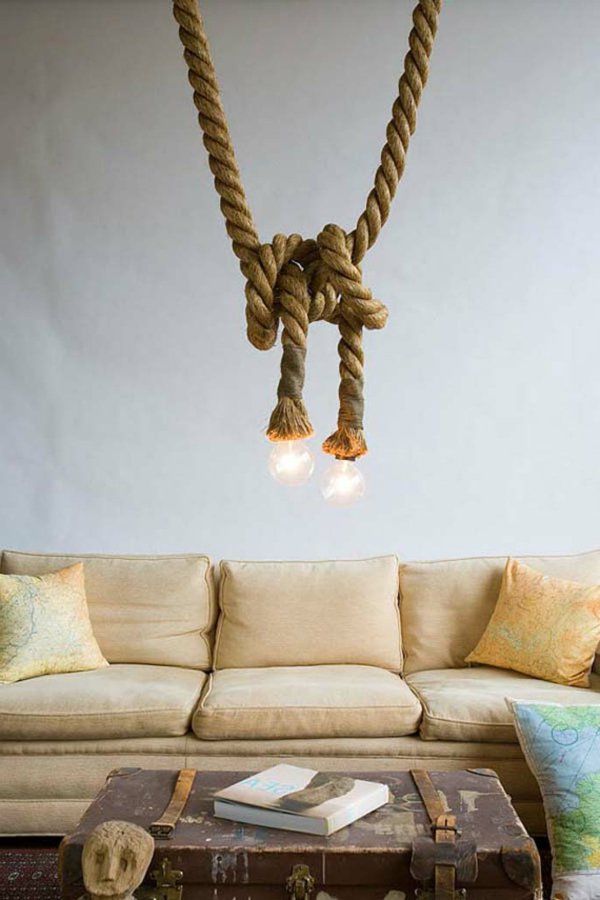 a living room with a couch, coffee table and rope light fixture hanging from the ceiling