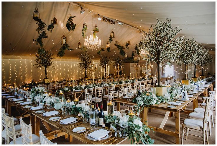 the tables are set up with candles and greenery for an elegant wedding reception in a marquee