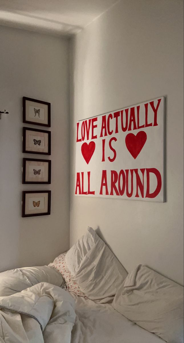 there is a bed with white sheets and pillows in the room that says love actually is all around