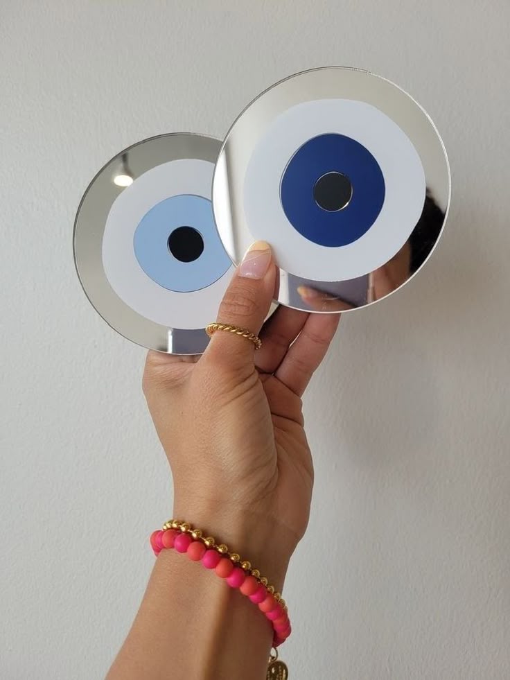 a hand holding two mirrors with blue eyes on them