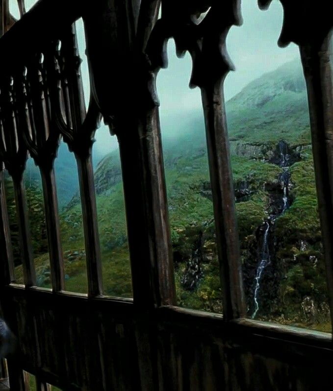 the view from inside an old building looking out at a waterfall and mountains in the distance