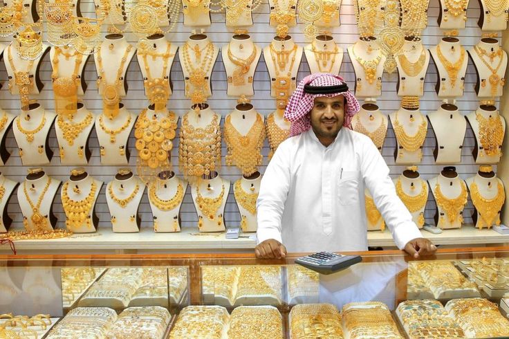 a man standing in front of a display case filled with gold jewelry