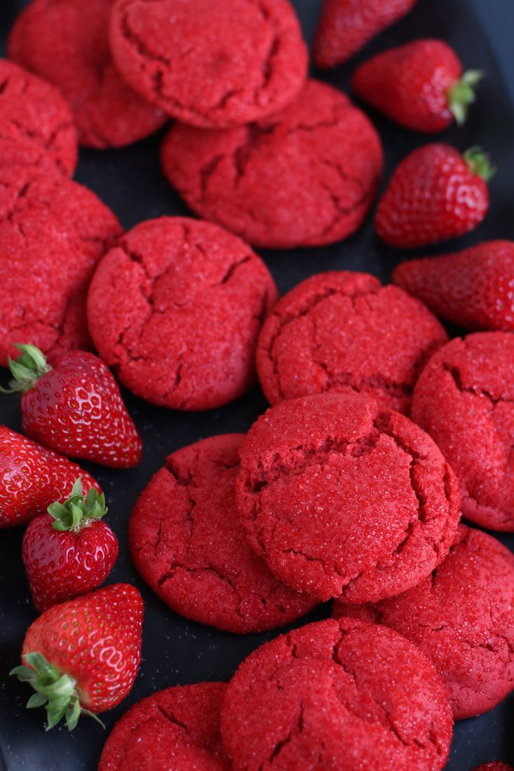 red cookies and strawberries on a black plate