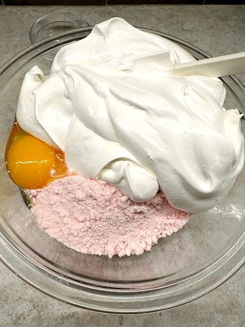 a glass bowl filled with whipped cream and an egg