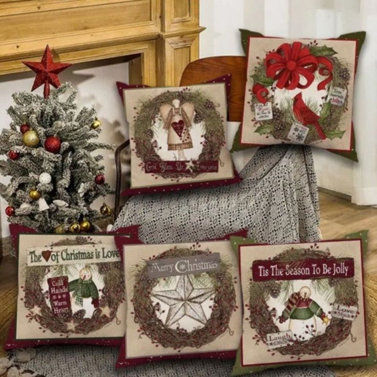 four christmas pillow cases with designs on them and a tree in the corner next to it