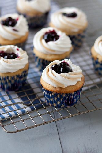 cupcakes with white frosting and blueberries on a cooling rack