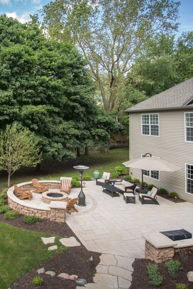 an outdoor patio with seating and fire pit surrounded by trees in the back yard area