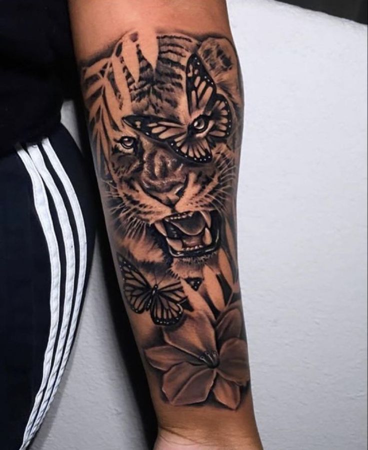 a person with a tiger tattoo on their arm and the other hand is holding a butterfly