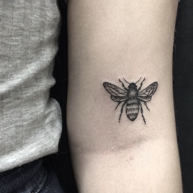 a black and white bee tattoo on the arm