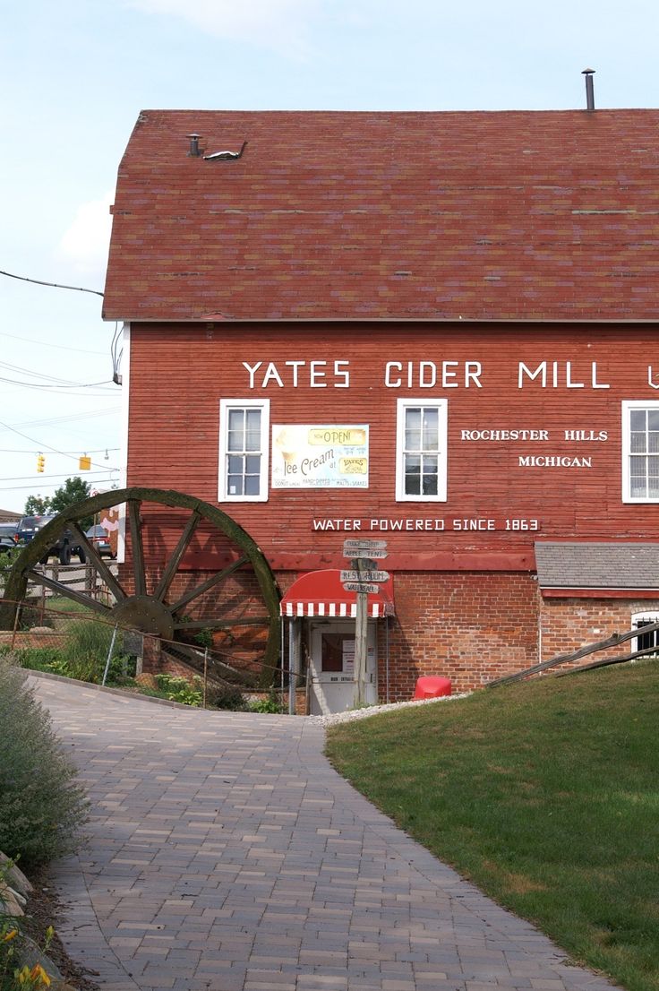 an old red brick building with a water wheel on the front and side of it