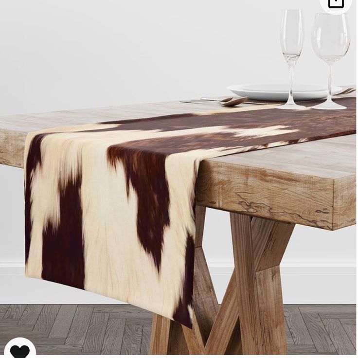 a cow print table runner on top of a wooden table with wine glasses in the background