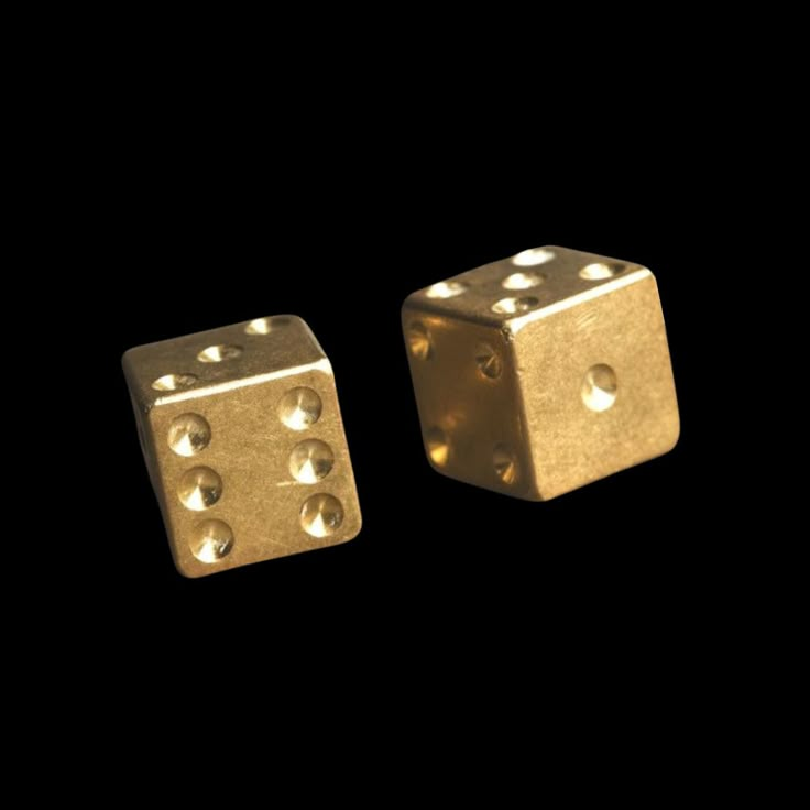 two gold dices sitting side by side on a black background, one has four holes in the middle