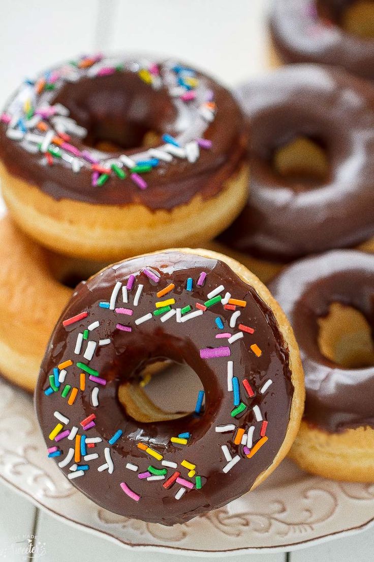 several donuts with chocolate frosting and sprinkles are on a plate