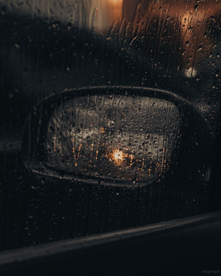 rain drops on the window of a car as it sits in front of a street light