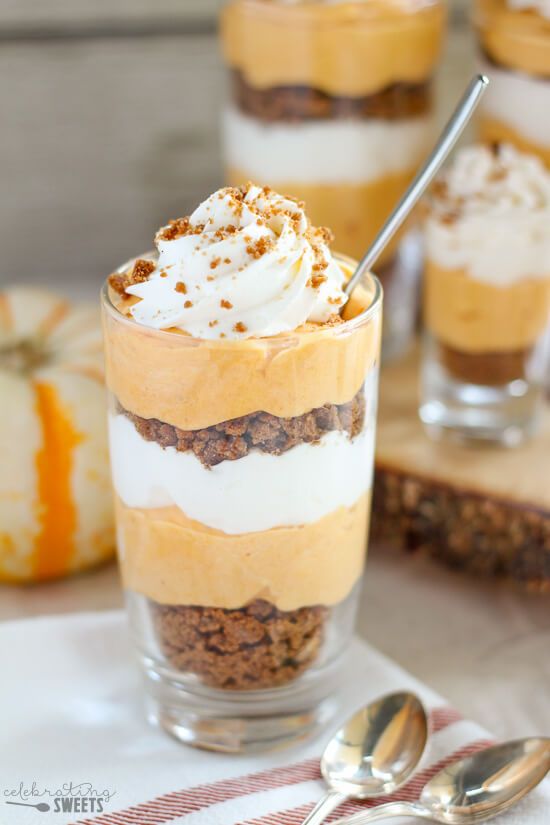 a dessert in a glass with whipped cream and other toppings on top, next to pumpkins