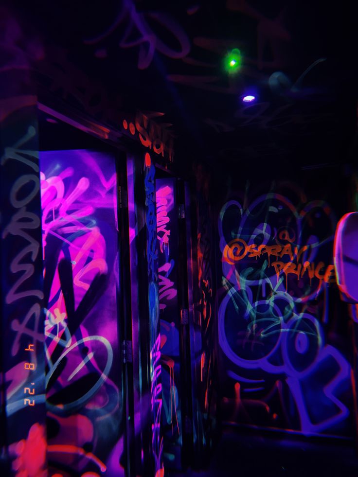 graffiti painted on the walls and doors of a room with neon lights in the dark