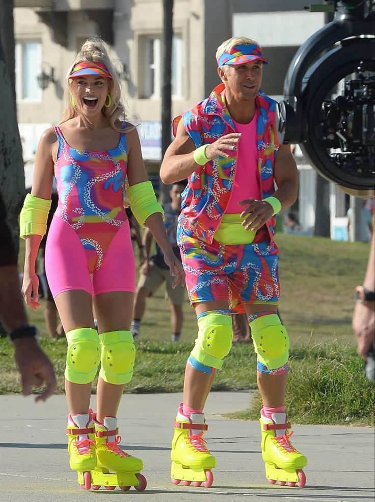 two people are rollerblading down the street in bright clothing and neon knee pads