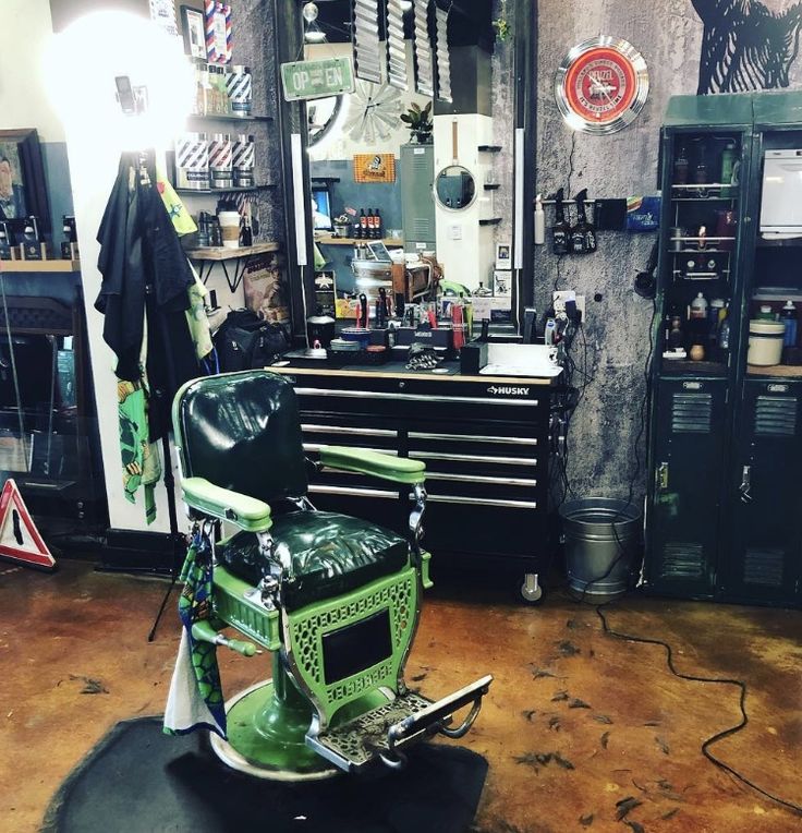 a green motorcycle parked in front of a garage with lots of tools on the wall