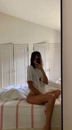 a woman sitting on top of a bed taking a selfie