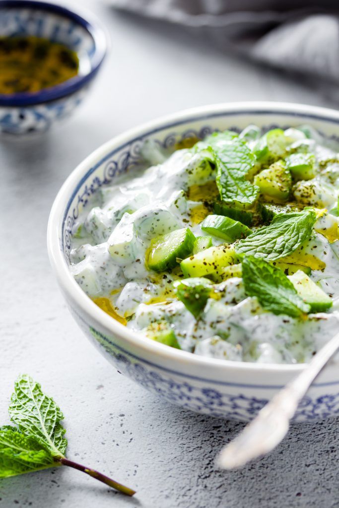 a bowl filled with cucumber, mint and yogurt on top of a table