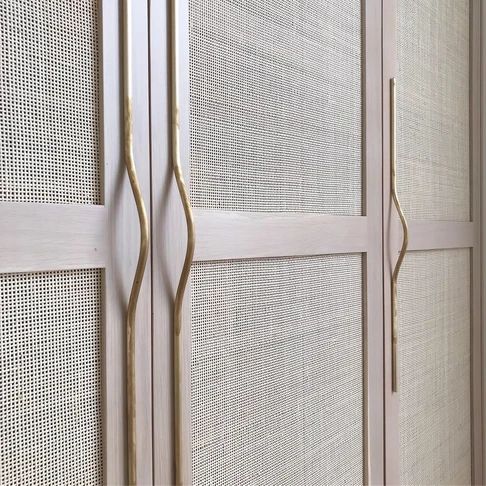 a white closet with gold handles and mesh doors