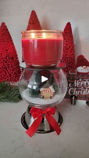 a red candle sitting on top of a glass bowl filled with snow and christmas decorations