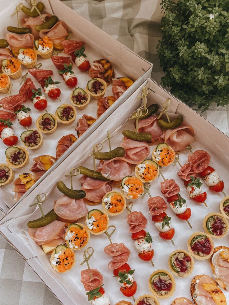 two boxes filled with different types of appetizers on top of a checkered table cloth