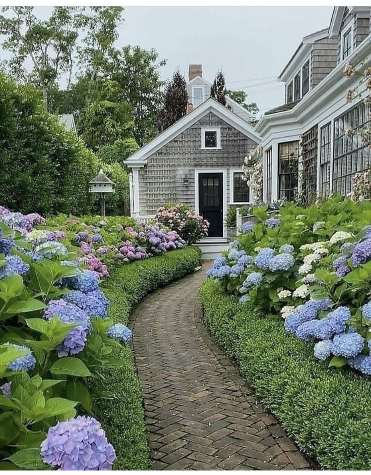 there is a pathway that leads to a house with many flowers in the front yard