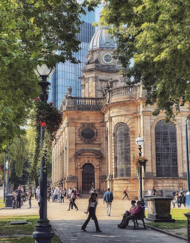 people are sitting on benches in front of an old building