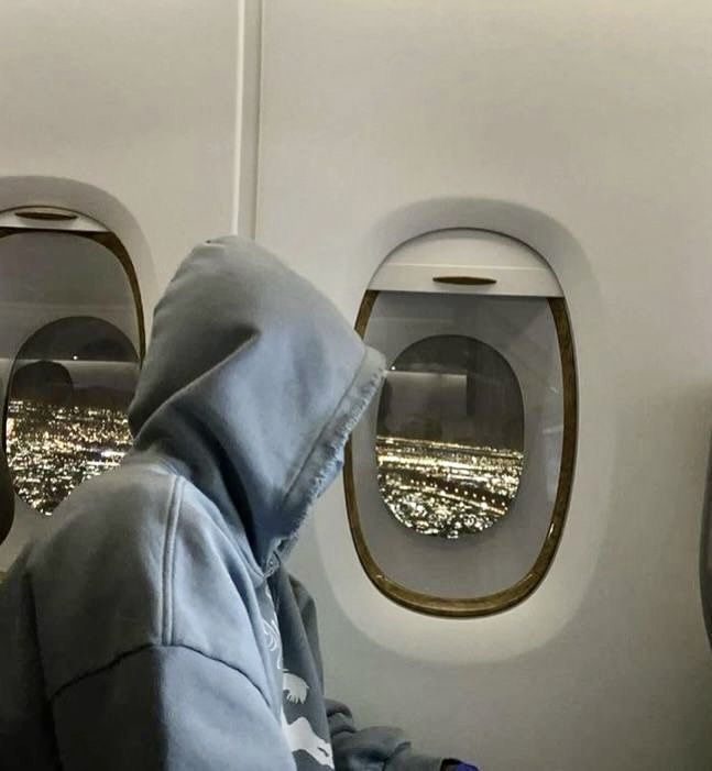 a person sitting in an airplane seat looking out the window at the city lights below