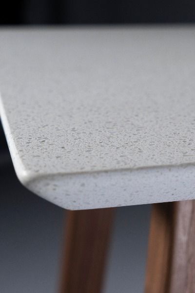 a close up view of a white table with wood legs and the edge of it