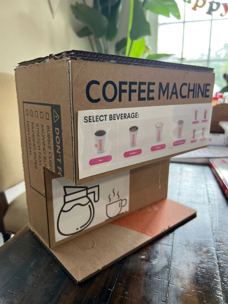 a coffee machine sitting on top of a wooden table next to a box that says coffee machine