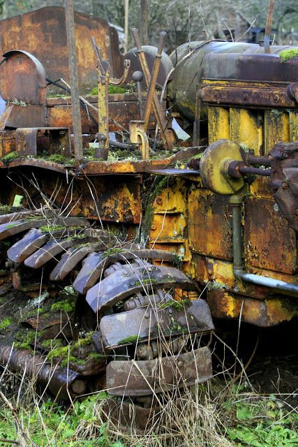 an old rusty tractor sitting in the grass